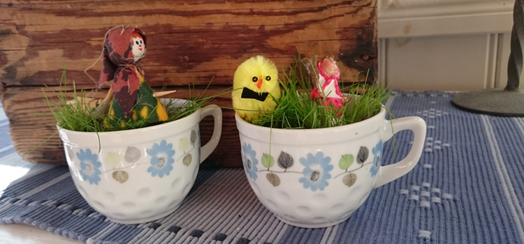 Prydnadsgräs i två koppar dekorerade med påskkärringar och kyckling